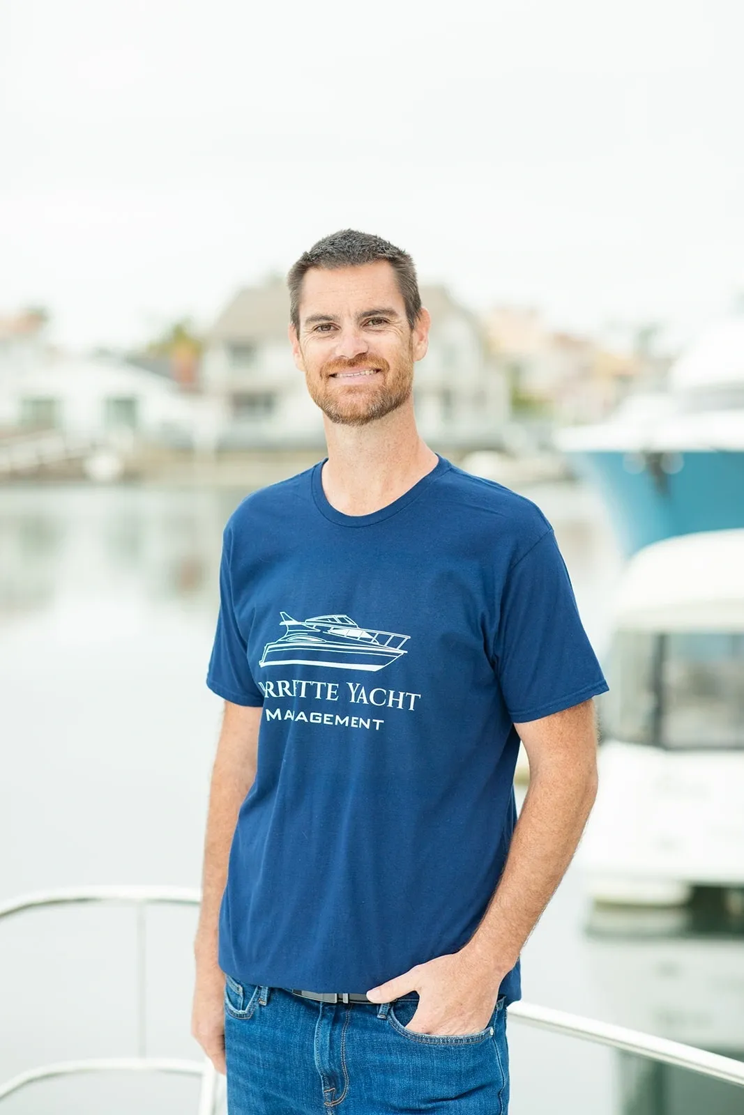 Man smiling by marina, wearing blue shirt.