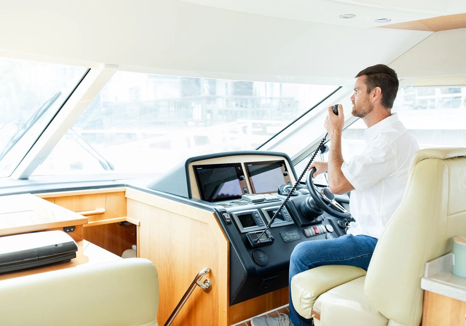 Man steering boat using communication device.
